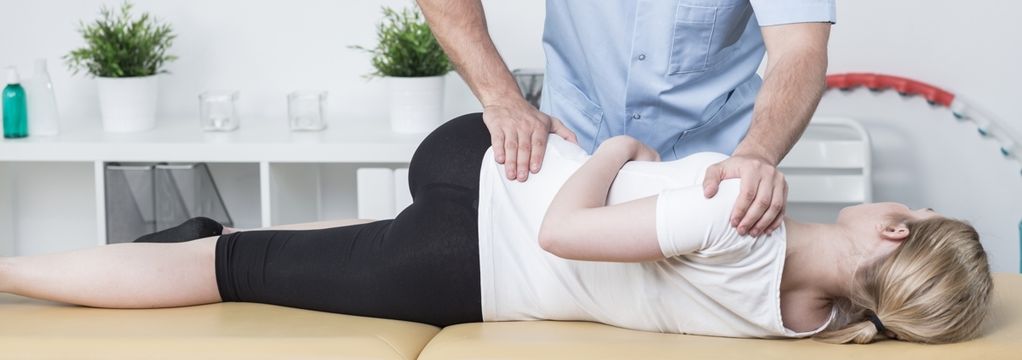 Osteopath performing gentle manual therapy on a patient's lower back